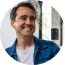 Man smiling in a casual denim jacket searches Atlas vs Ahrefs to compare backlink analyzer tools.
