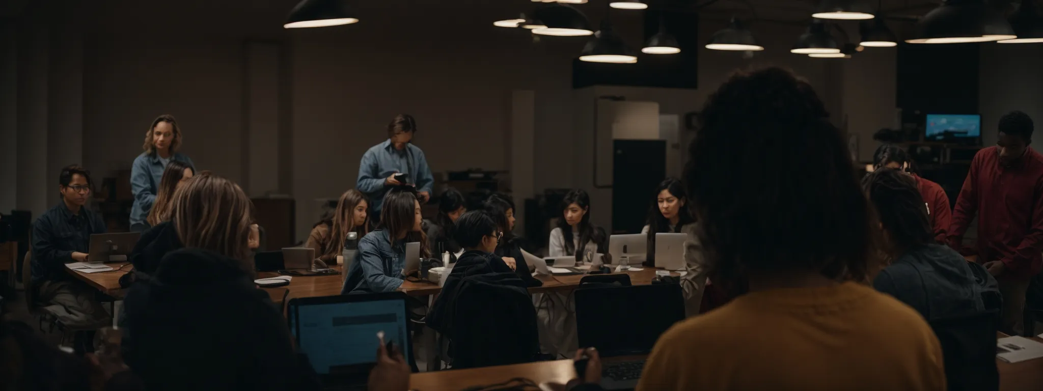 a diverse group of people engaged in a workshop with laptops open, collaborating on a project.