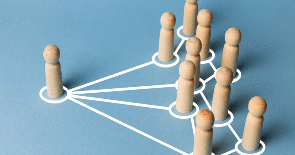 Wooden figures stand connected by white lines on a blue surface, illustrating an organizational structure that embodies thought leadership.