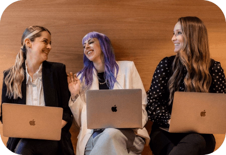 Search Atlas team members collaborating with laptops and smiling during a casual work session in office